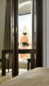 a woman standing on a balcony looking out of a window at The Siggiewi Suites in Siġġiewi