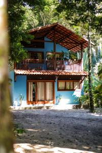 a blue house with a balcony on top of it at Chalés Cumuruxatiba in Cumuruxatiba