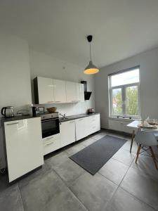 kuchnia z białymi szafkami, stołem i oknem w obiekcie Air Apartments 3 w Bremie
