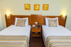 a hotel room with two beds and a night stand at Quality Porto Alegre in Porto Alegre