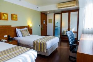 a hotel room with two beds and a chair at Quality Porto Alegre in Porto Alegre