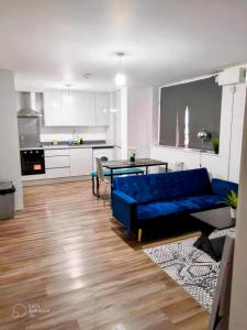a living room with a blue couch and a kitchen at Urban 2 Bedroom with Parking in West Bromwich