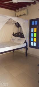 a bed with a canopy in a room with a window at New Mahrus Hotel Lamu in Lamu