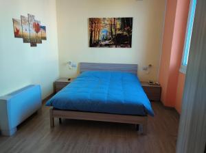 Un dormitorio con una cama azul y una pintura en la pared en Villa ARA blu, en Canegrate