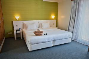 a bedroom with a large white bed with a basket on it at Hotel Varandas do Atlântico by RIDAN Hotels in Praia da Vitória