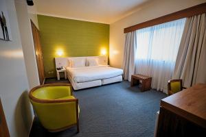 a hotel room with a bed and two chairs at Hotel Varandas do Atlântico by RIDAN Hotels in Praia da Vitória