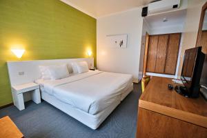 a bedroom with a large white bed and a television at Hotel Varandas do Atlântico by RIDAN Hotels in Praia da Vitória