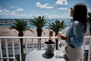 a woman standing on a balcony looking out at the beach at Hotel Varandas do Atlântico by RIDAN Hotels in Praia da Vitória