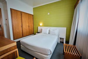 a bedroom with a white bed and a wooden cabinet at Hotel Varandas do Atlântico by RIDAN Hotels in Praia da Vitória