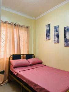 een slaapkamer met een bed met roze lakens en een raam bij Clementine’s Subdivision House in Oroquieta