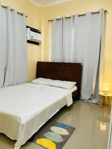 a bedroom with a bed with white curtains and a rug at Clementine’s Subdivision House in Oroquieta