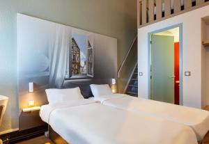 two white beds in a room with a staircase at B&B HOTEL CHARTRES Le Forum in Chartres