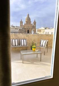 Siġġiewi的住宿－The Siggiewi Suites，阳台配有2把椅子和1张桌子。
