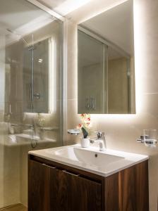 uma casa de banho com um lavatório e um espelho grande em The Siggiewi Suites em Siġġiewi