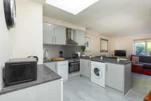 a kitchen with white cabinets and a living room at Bright & Contemporary 1bedroom Annexe - Herne Hill! in London