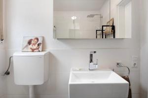 a white bathroom with a sink and a mirror at Apartment Dreiländer Blick in Wintersweiler +14 photos