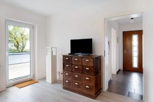 a room with a television on a dresser with a window at Apartment Dreiländer Blick 