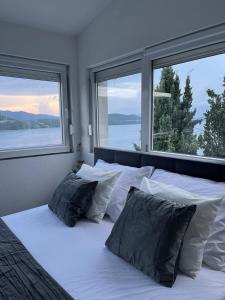 a bedroom with a white bed with two windows at Villa Grande in Neum