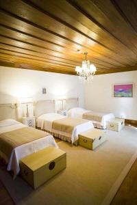 una camera con tre letti e un lampadario a braccio di Casa da Mina a Mondim da Beira