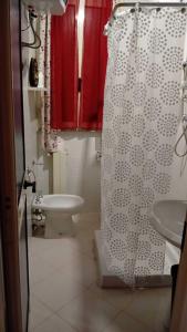 y baño con cortina de ducha blanca y aseo. en La casetta di Ele, en Sassari