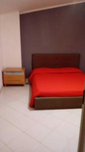 1 dormitorio con cama roja y mesita de noche en La casetta di Ele, en Sassari
