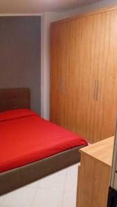1 dormitorio con cama roja y armarios de madera en La casetta di Ele, en Sassari
