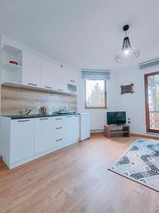 uma cozinha com armários brancos e piso em madeira em Apartments Planinski raj em Travnik