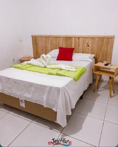 a bed with a red pillow on top of it at Pousada Jeri Flats in Jericoacoara