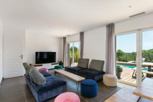ein Wohnzimmer mit zwei Sofas und einem Fernseher in der Unterkunft Villa Le Golf St Thomas 19 pers in Béziers