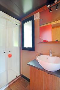 La salle de bains est pourvue d'un lavabo blanc et d'une douche. dans l'établissement Huttopia Fontvieille, à Fontvieille