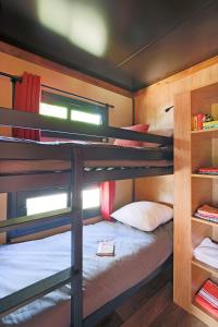 Huttopia Fontvieille في فونتفيل: سرير بطابقين في غرفة مع سرير بطابقين في منزل