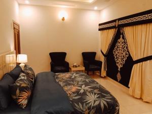 a bedroom with a bed and two chairs in it at Dream Inn Guest House in Islamabad