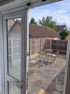 uma porta de vidro deslizante com uma mesa e cadeiras num pátio em Exquisite Holiday Home 3 minutes from Dartford Station em Kent