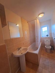 uma casa de banho com um lavatório, uma banheira e um WC. em Exquisite Holiday Home 3 minutes from Dartford Station em Kent
