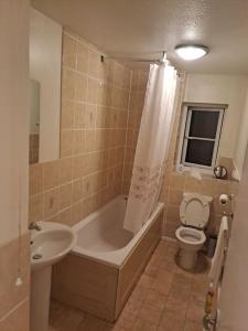 a bathroom with a tub and a toilet and a sink at Exquisite Holiday Home 3 minutes from Dartford Station in Kent