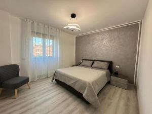 a bedroom with a large bed and a chair at Sempione Apartment in Lainate