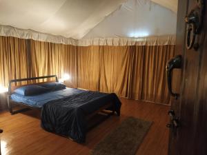 een slaapkamer met een bed in een kamer met gordijnen bij Trident Jungle Stay in Dandeli