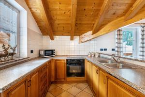 - une cuisine avec des placards en bois et un évier dans l'établissement Casa Titol Giuseppe, à Pozza di Fassa