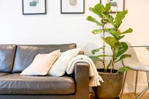a leather couch with pillows and a potted plant at Apartment by Spitalfields & Liverpool Street Station in London