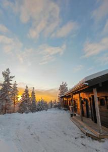 een hut in de sneeuw met de zonsondergang op de achtergrond bij Rukan Tunturipöllö in Kuusamo +12 foto's