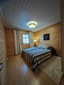 een slaapkamer met een bed in een houten kamer bij Rukan Tunturipöllö in Kuusamo