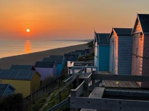 a row of beach huts on the beach at sunset at The Old Post Office in Lymington