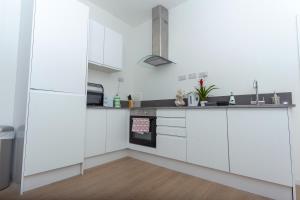 cocina con armarios blancos y fogones en One bedroom serviced apartment Smethwick F312, en Birmingham