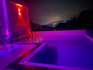 a room with a pool with chairs and purple lights at Aurelia inn in Kandy