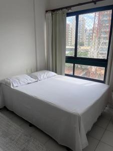 a bed in a room with a large window at Loft Pituba Sol in Salvador