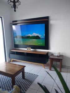 uma sala de estar com uma grande televisão de ecrã plano na parede em WI-FI 600MEGA 8 pessoas CENTRO da cidade frente mar 3quartos 2 carros em Mongaguá