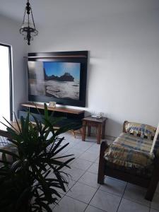 sala de estar con TV de pantalla plana en la pared en WI-FI 600MEGA 8 pessoas CENTRO da cidade frente mar 3quartos 2 carros en Mongaguá