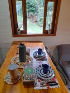 una mesa de madera con tazas y platillos. en Chalé Brisa do Vale, en Santa Luísa de Baixo