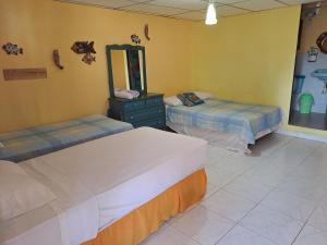 two beds in a room with a mirror and a dresser at Villa Bella in Portobelo