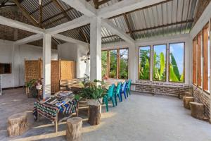 Habitación con mesa, sillas y ventanas. en Palulu Garden Homestay en Labuan Bajo